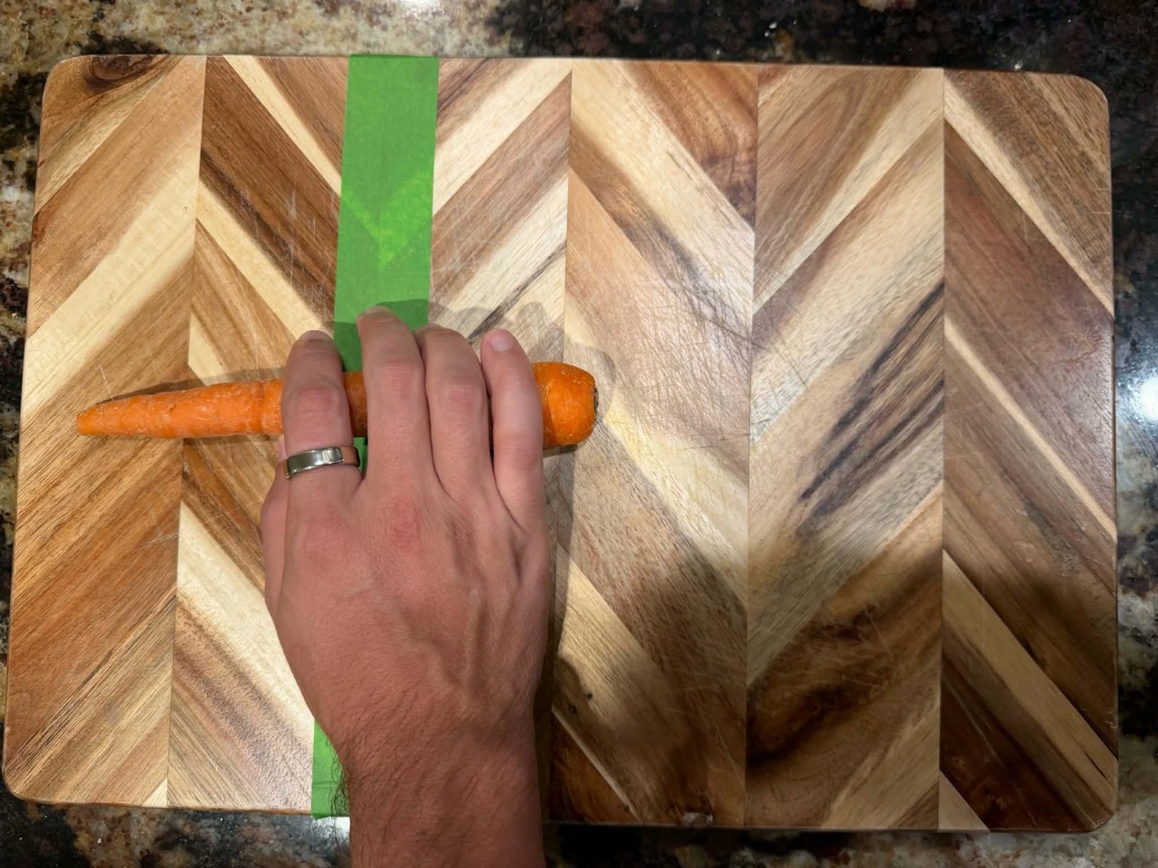 Original photograph of a hand covering the carrot at the marked cutting line.
